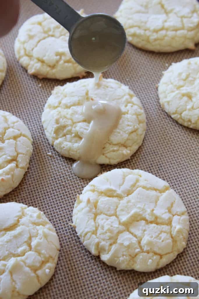A close-up of Kentucky Butter Cake Cookies with a glistening glaze, ready for a sprinkle of powdered sugar. Keywords: butter cake glaze, cookie recipe, sweet treat.