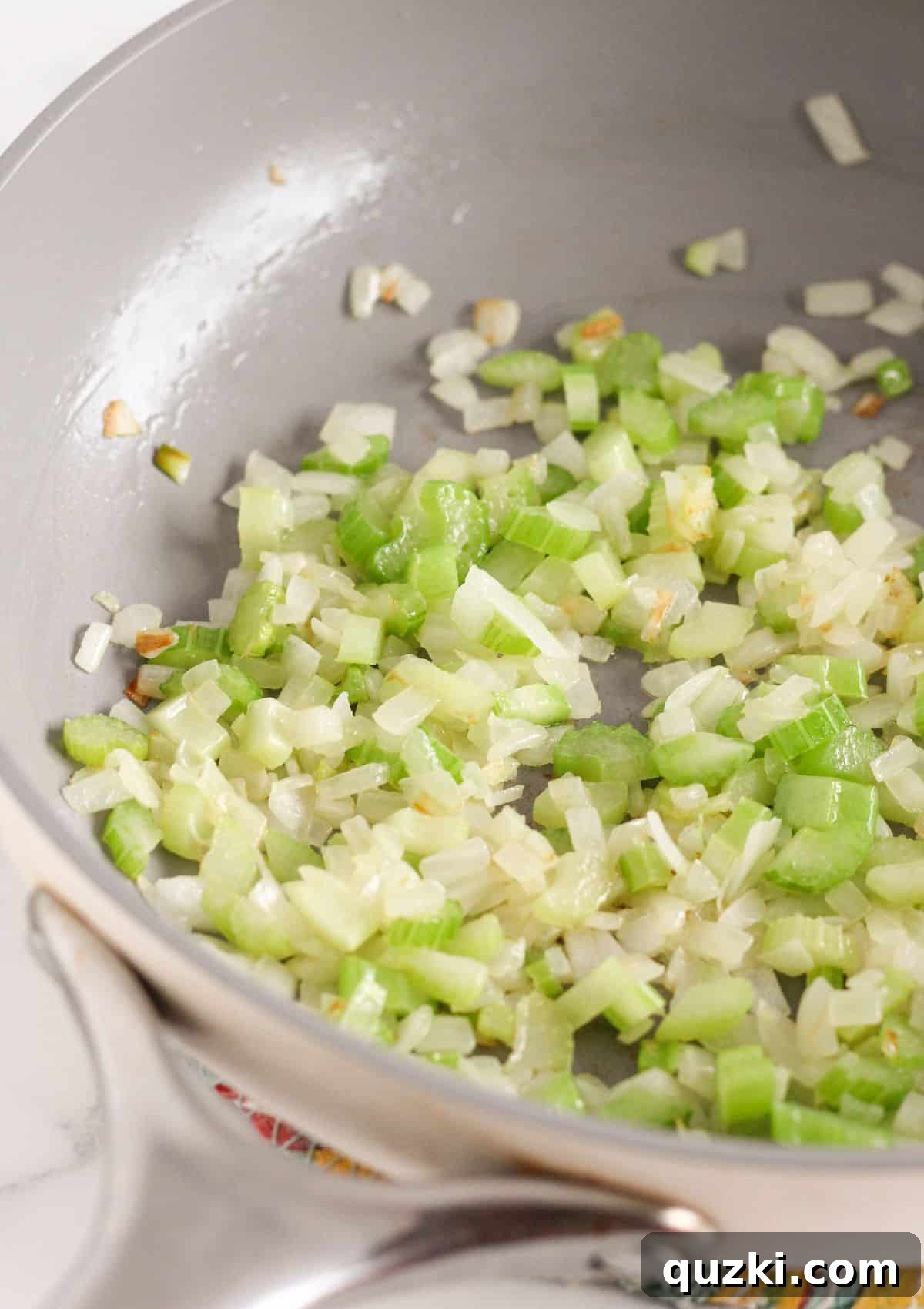 Cooking chopped onion and celery in melted butter in a large pan on the stovetop until softened.