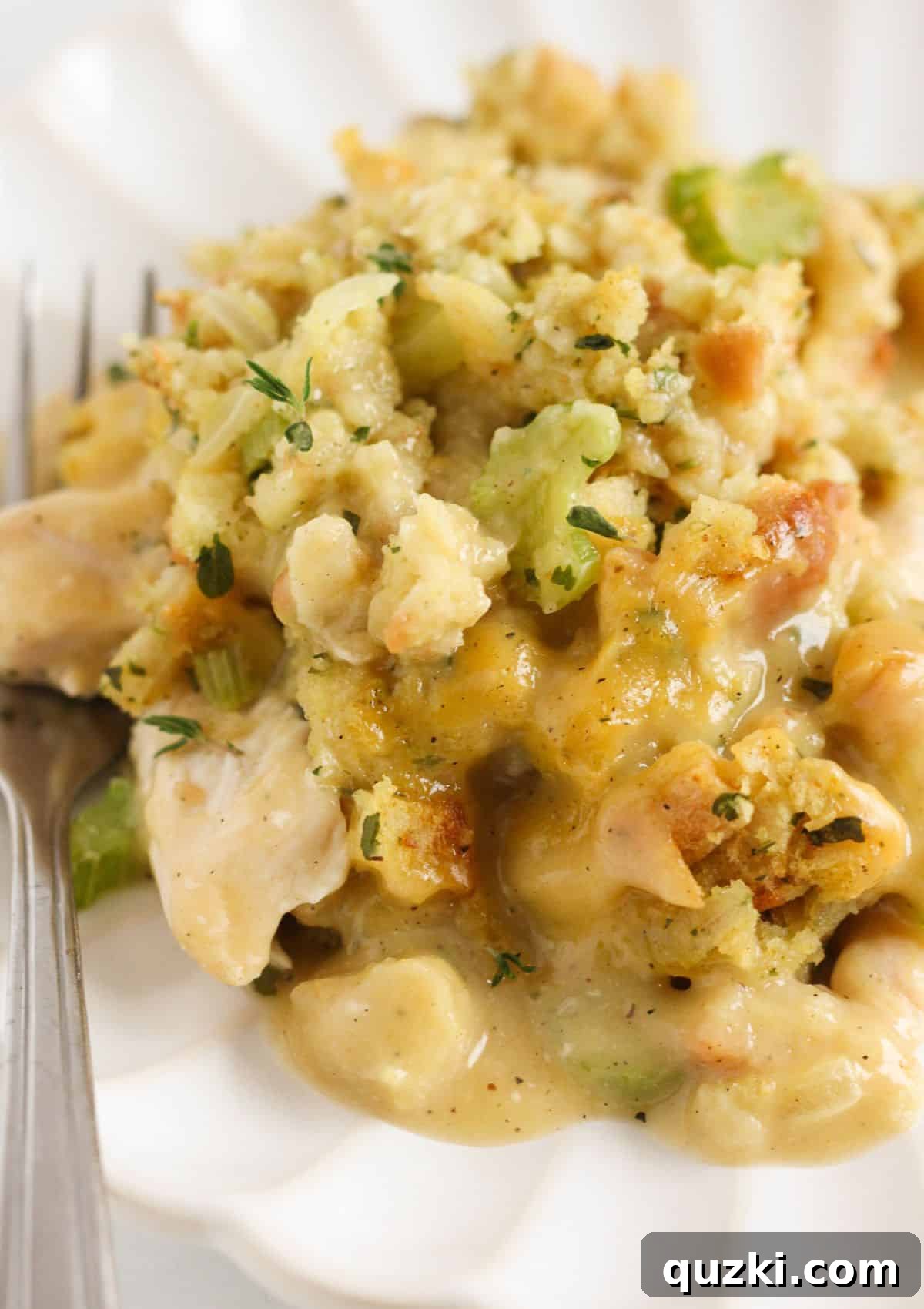A generous serving of baked chicken and stuffing casserole presented on a plate, garnished with fresh herbs.