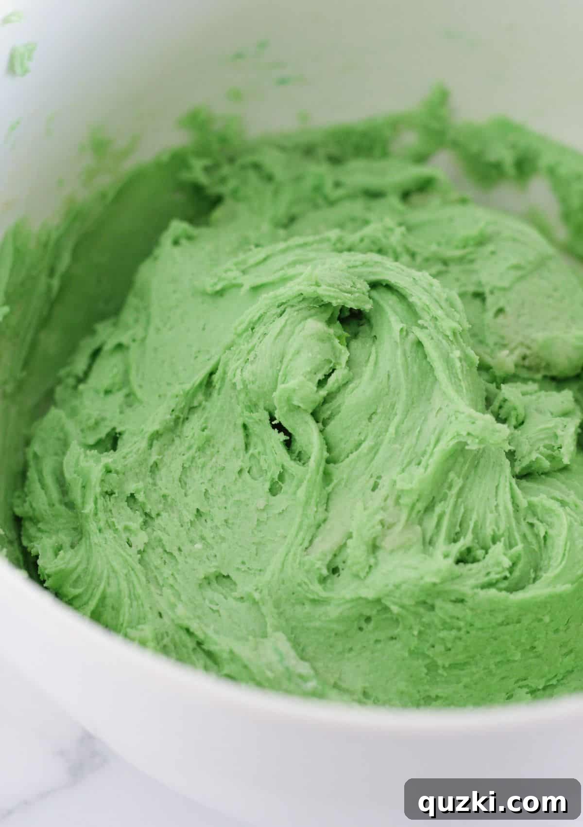 The finished vibrant green Grinch cookie dough in a mixing bowl.