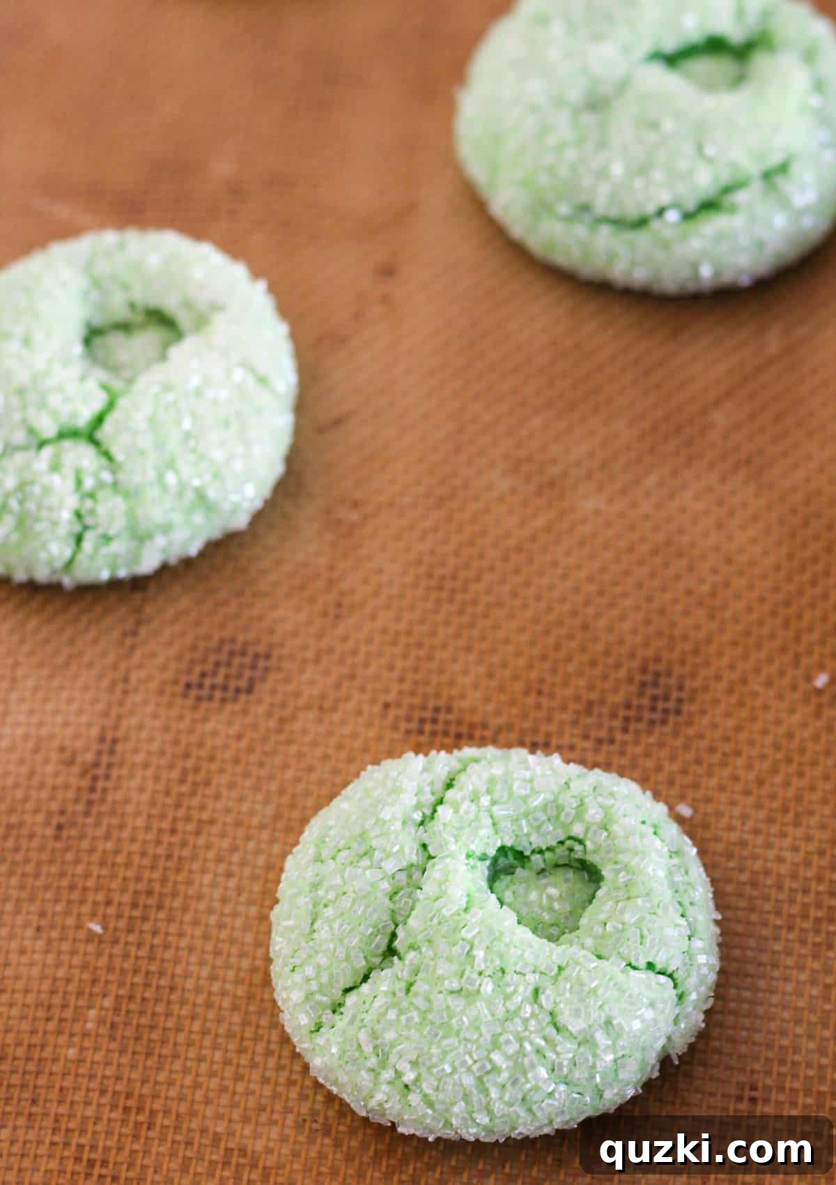 Making the heart indentation in a freshly baked green cookie with a pinky finger.