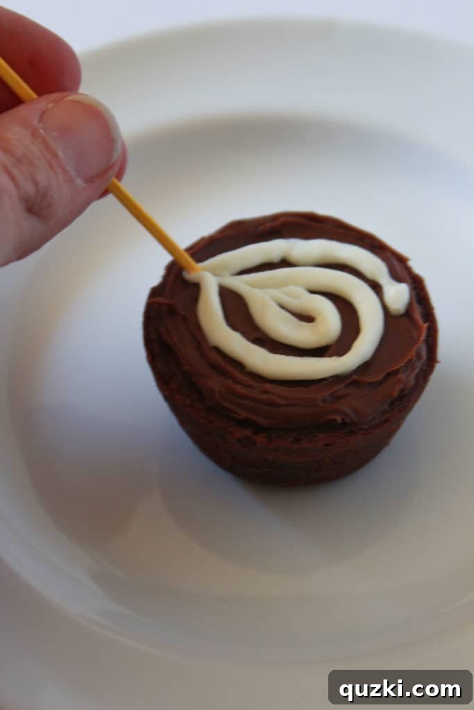Ghoulishly Good Halloween Brownie Bites 6 Detailed step-by-step image showing a toothpick dragging through vanilla frosting on a chocolate-frosted brownie to create a spider web pattern.