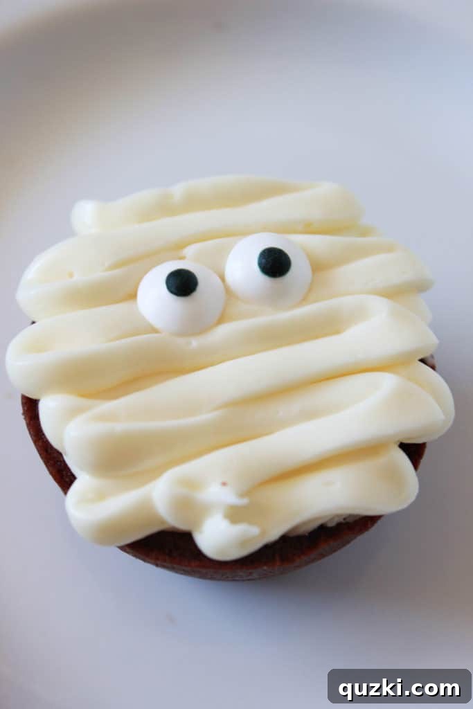 Ghoulishly Good Halloween Brownie Bites 9 A finished Mummy Halloween Brownie Bite with two edible eyeballs peeking out from vanilla frosting bandages.