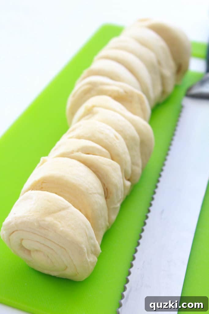 Spicy Jalapeño Crescent Poppers 3 Slicing refrigerated crescent roll dough into even pieces with a serrated knife for Jalapeno Popper Crescent Bites.