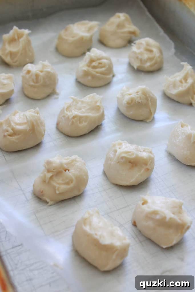 Pumpkin Swirl Cookies 3 Steps for preparing cream cheese frosting for pumpkin roll cookies: spooning mixture onto parchment paper.