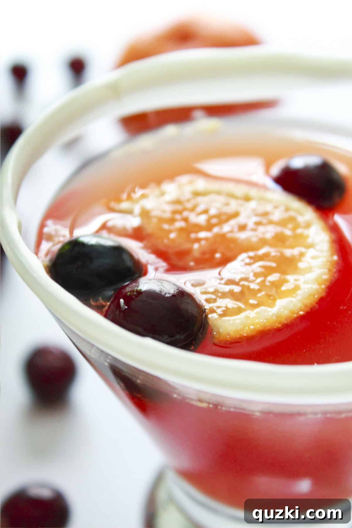 A cranberry mimosa with a white chocolate rim and fresh cranberries, ready for a festive toast.