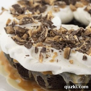 A finished Better Than Anything Cake with whipped topping and chopped candy bar, ready to be enjoyed.