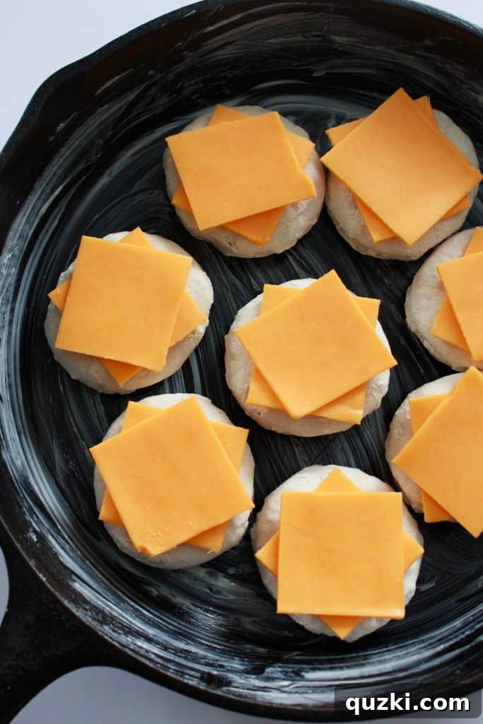 Cheddar cheese quarters placed on top of each biscuit in the skillet.