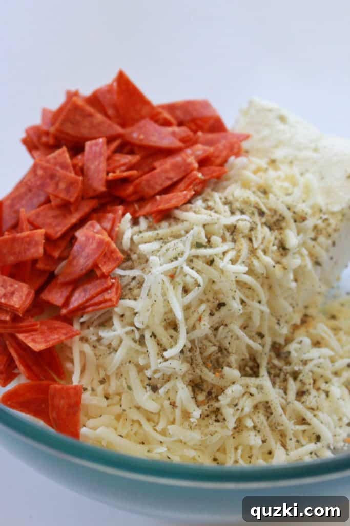 Ingredients for the pizza dip (cream cheese, mozzarella, pepperoni, mayonnaise, Italian seasoning, garlic powder) mixed in a bowl
