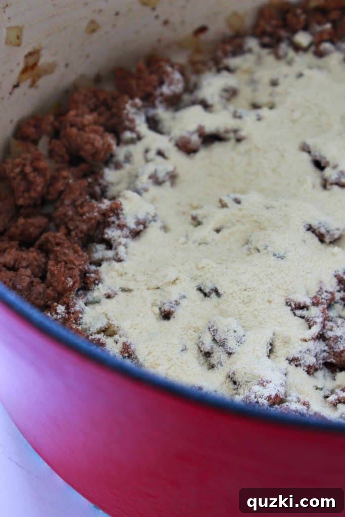Adding beef stock to the beef and Masa Harina mixture for a thick chili base.