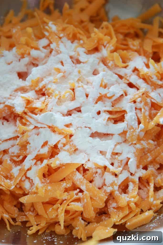 Classic Homemade Macaroni and Cheese 3 Combining freshly shredded cheddar cheese and cornstarch in a bowl, a key step for the no-roux method.