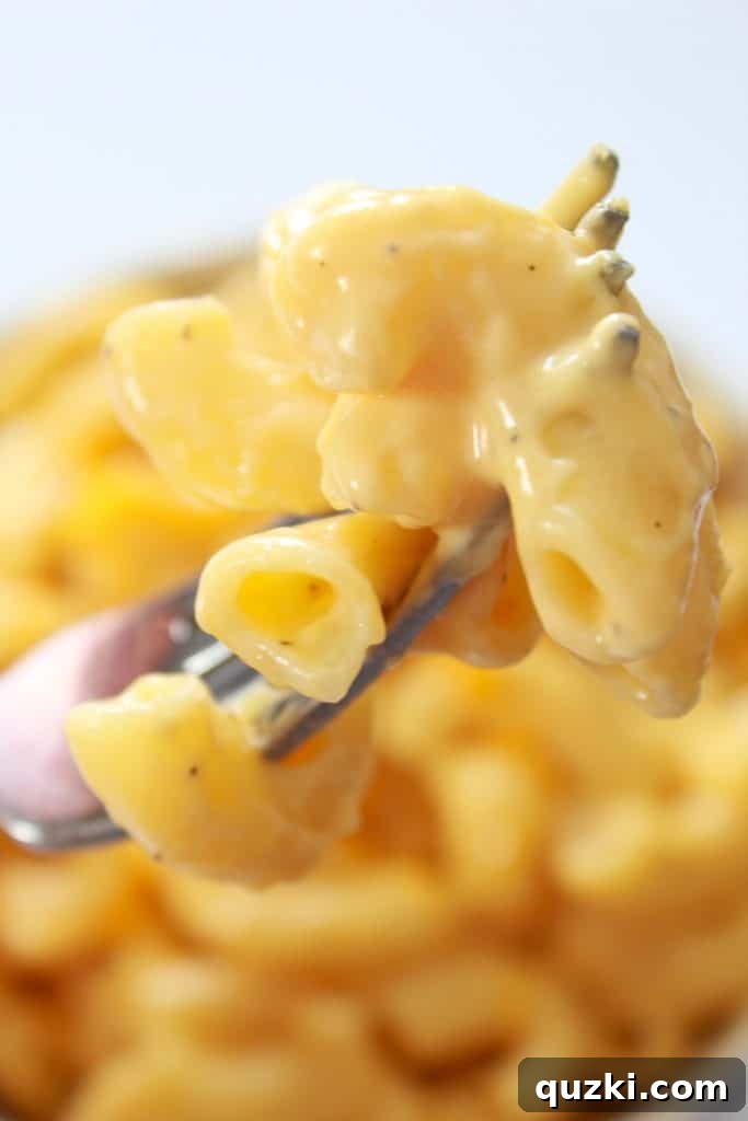 Classic Homemade Macaroni and Cheese 7 A fork laden with a spoonful of homemade macaroni and cheese, showing its creamy texture and delicious appeal, ready for tasting.