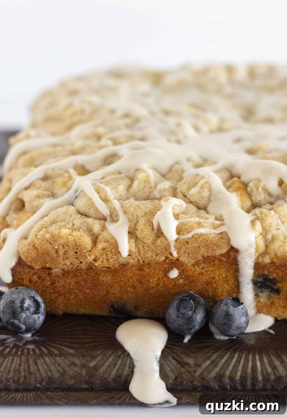Effortless Blueberry Muffin Cake 7 A fresh blueberry muffin cake with a drizzle of glaze.