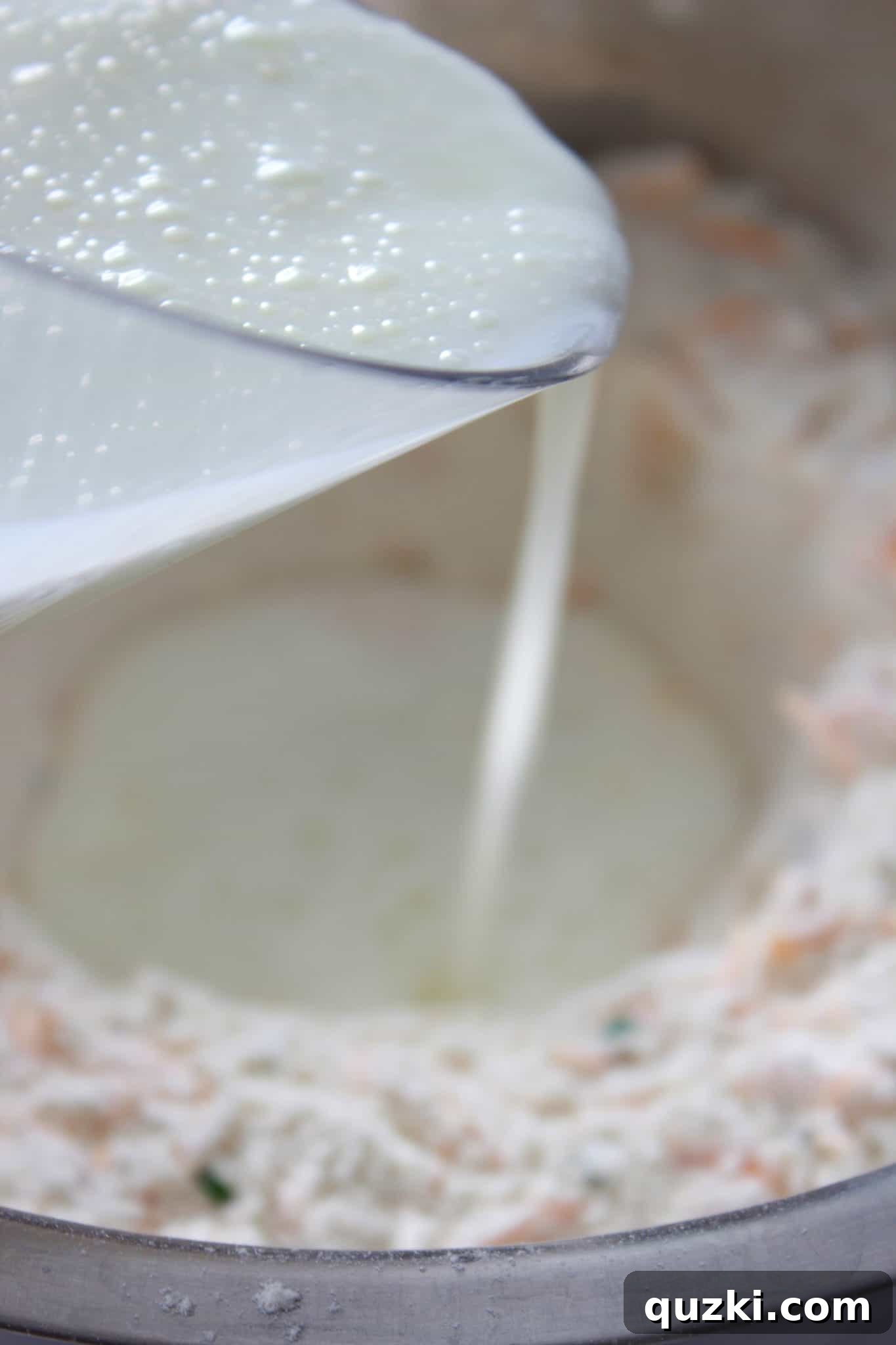 Adding the wet ingredients, specifically milk, to the dry mixture to begin forming the dough for the soda bread.