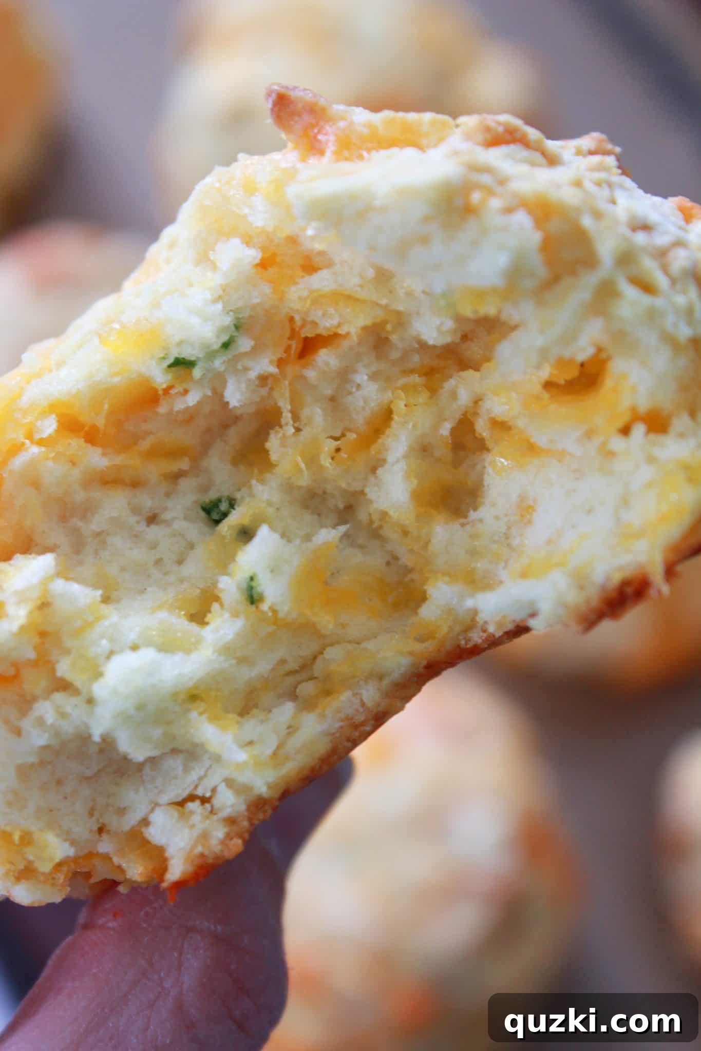 A close-up view of a sliced mini Irish soda bread, revealing the beautiful interior filled with melted cheddar and fresh chives.