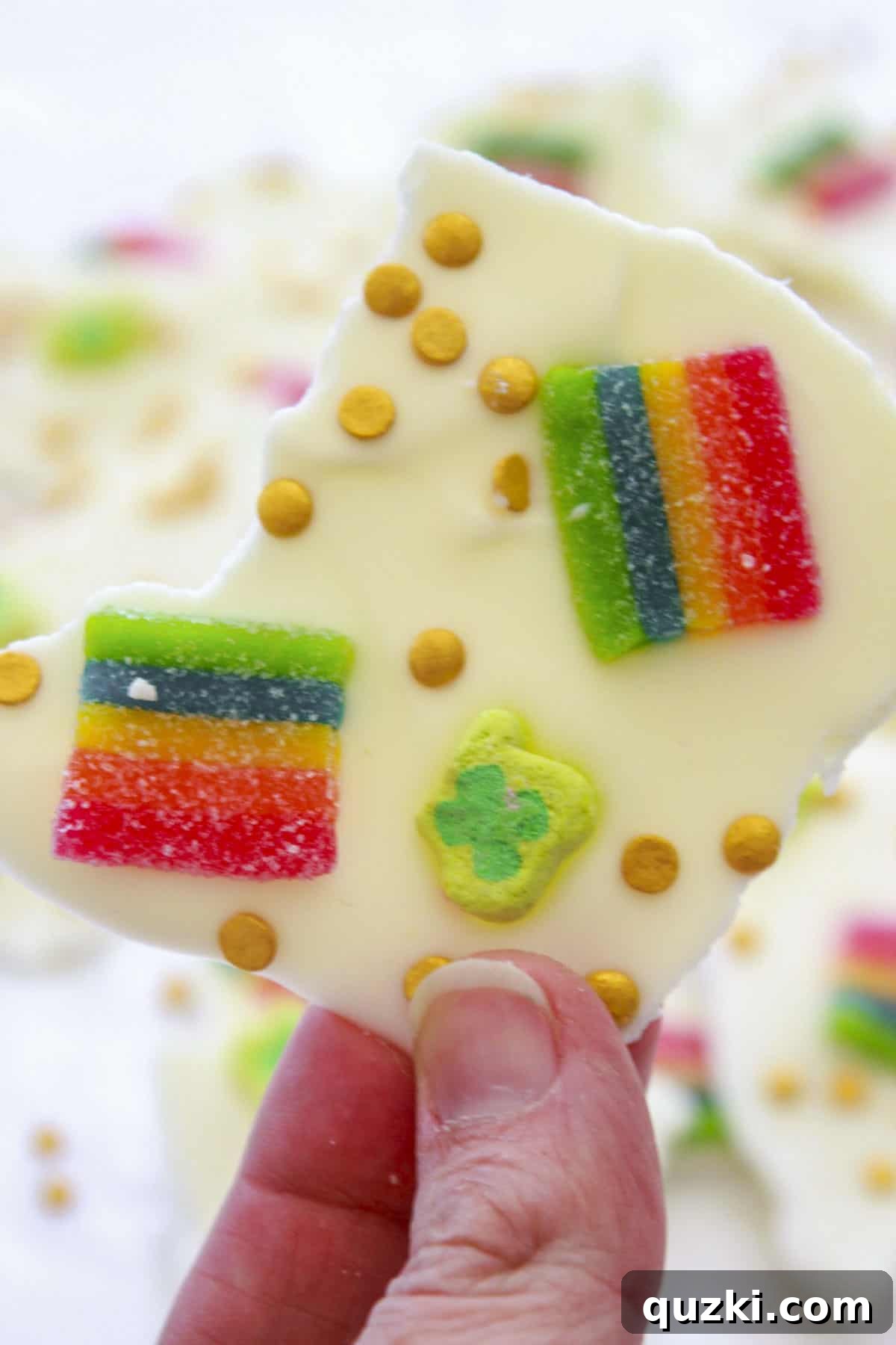 Lucky Leprechaun No-Bake Bark 6 A close-up of a perfectly broken piece of finished Leprechaun Bark, held in a hand, showcasing all its colorful toppings.