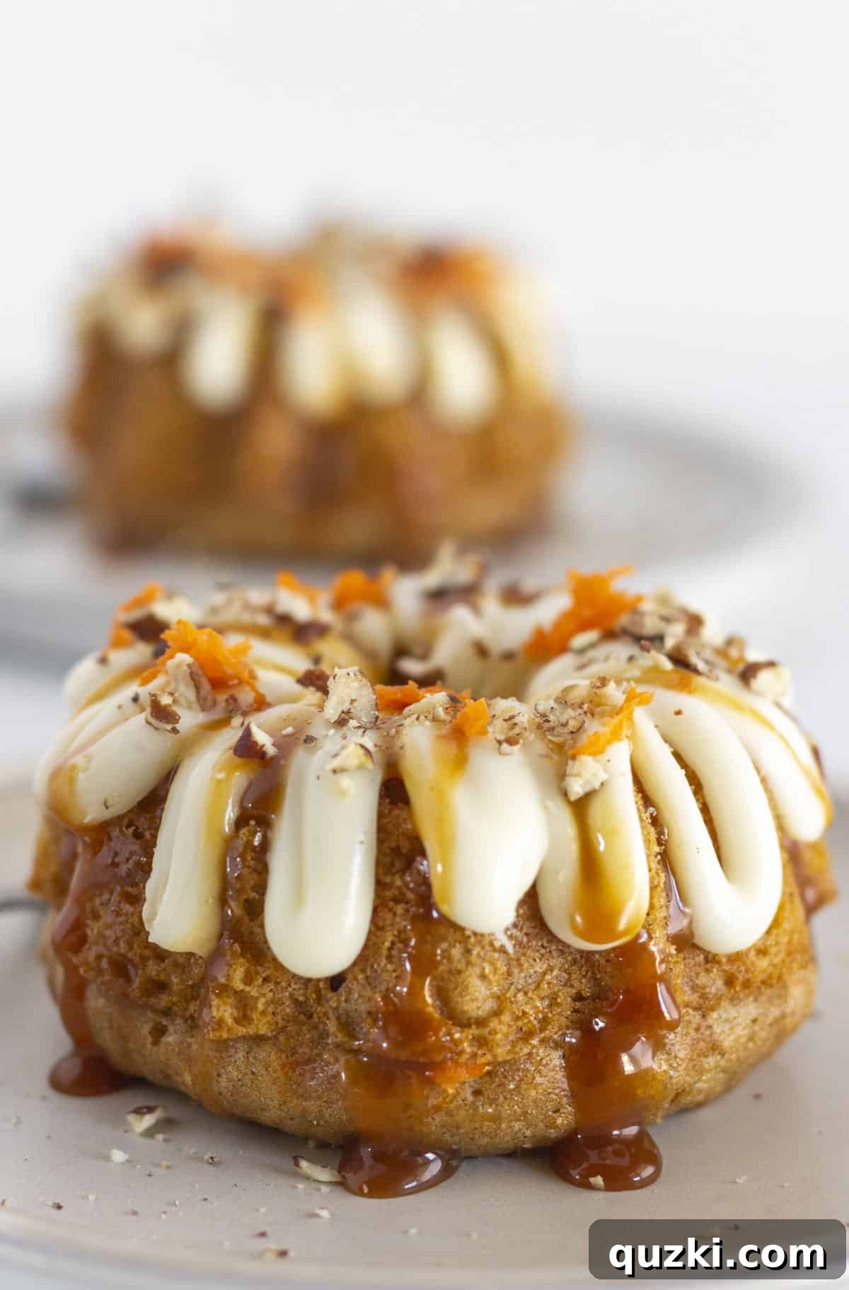 Effortless Mini Carrot Bundts 7 Two beautifully frosted mini carrot bundt cakes, ready to be served, on individual plates.