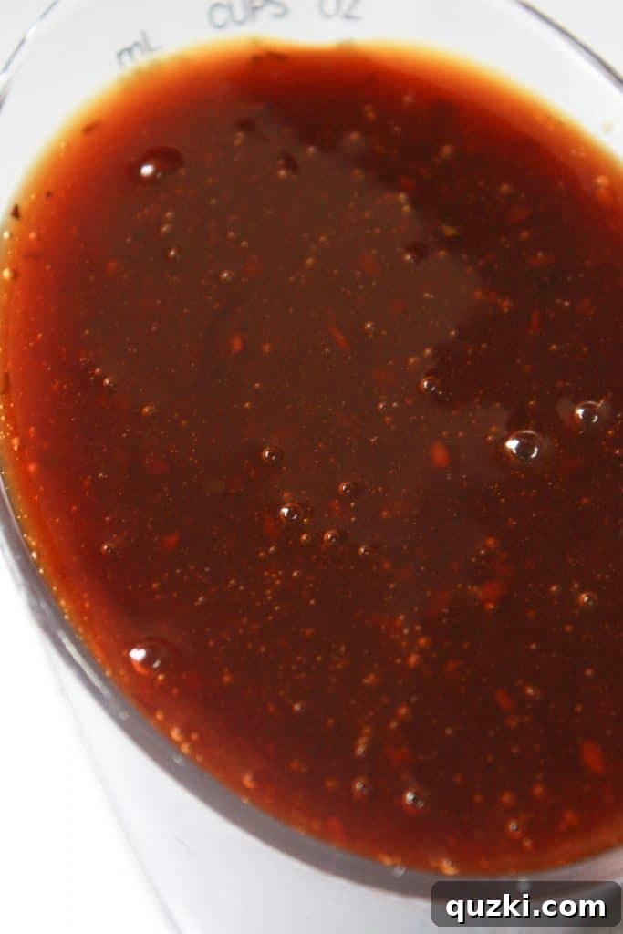 A measuring cup filled with rich, dark teriyaki sauce, ready to be added to the casserole ingredients.