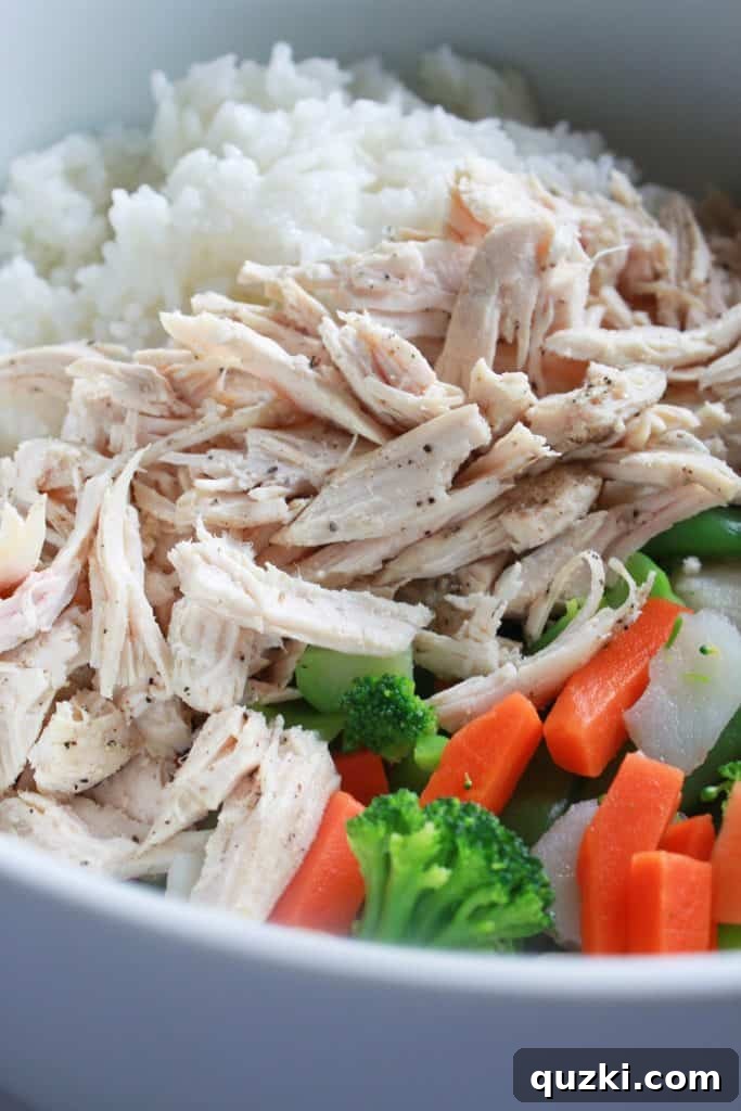 All the main components – shredded chicken, cooked rice, and stir-fry vegetables – combined in a large bowl, forming the base of the casserole.