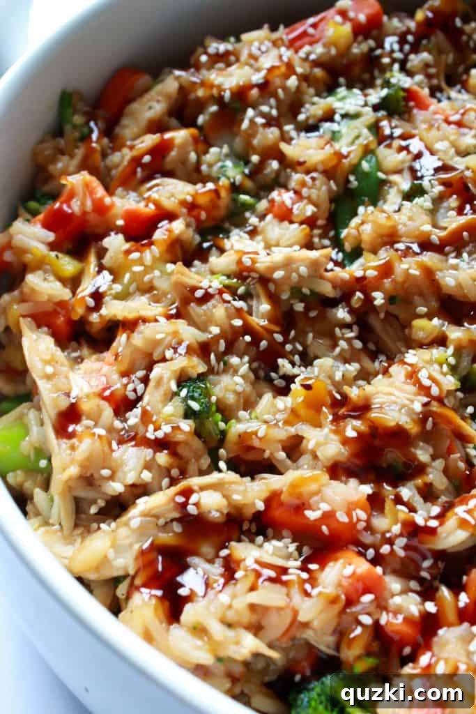 The baked Teriyaki Chicken Stir Fry Casserole, hot and bubbly, being garnished with a final drizzle of teriyaki sauce and a sprinkle of sesame seeds.
