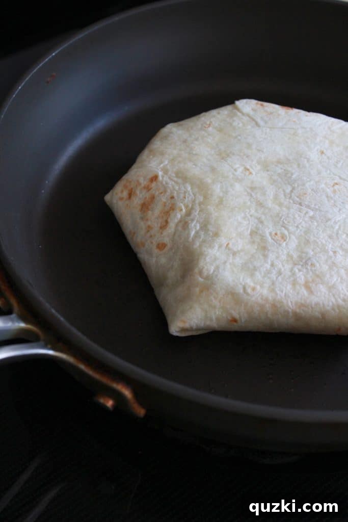 Golden Crunch Pocket 11 Step 8: Placing the folded Crunchy Wrap, seam-side down, into a non-stick pan to begin cooking.