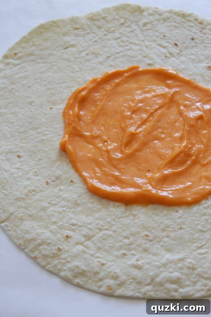 Golden Crunch Pocket 4 Step 1: Spreading warm nacho cheese sauce on a large burrito tortilla for the homemade Crunchy Wrap.