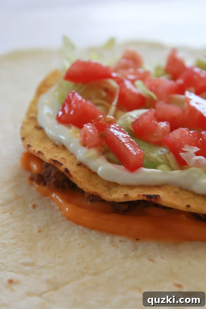Golden Crunch Pocket 7 Step 4: Adding a layer of sour cream, shredded lettuce, and diced tomatoes on the tostada shell.