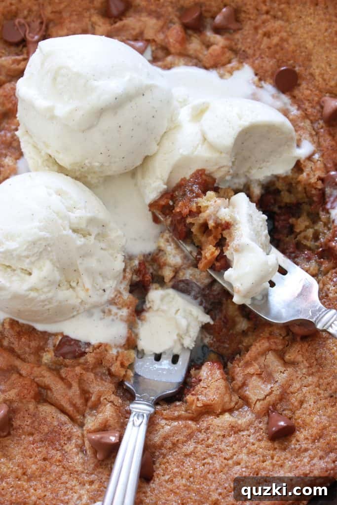 Decadent Skillet Chocolate Chip Cookie 11 A close-up shot of a Chocolate Chip Skillet Pizookie with ice cream, forks digging in, showcasing the ultimate dessert experience