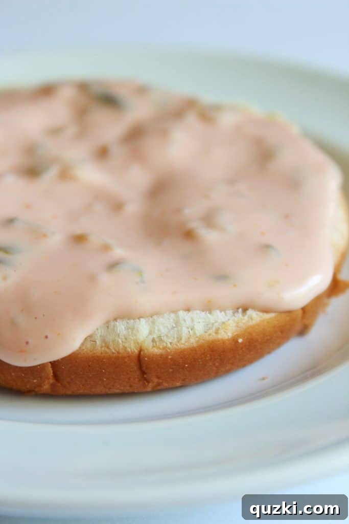 Bottom hamburger bun with a layer of secret sauce