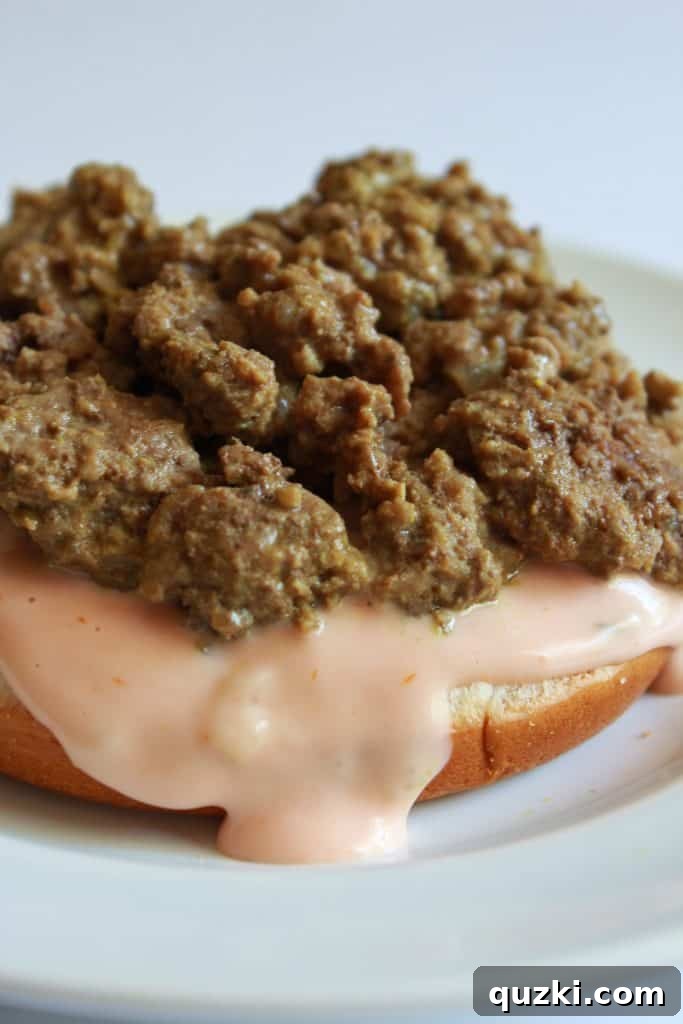 Meat mixture layered over the secret sauce on a bun