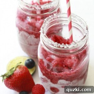 Two vibrant mixed fruit frozen daiquiris in mason jars, garnished with fresh berries and straws, ready to be enjoyed on a sunny day.
