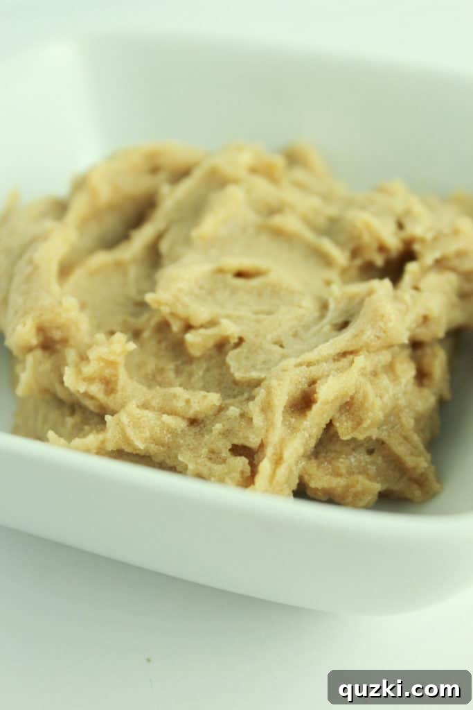 Granulated sugar being slowly added to the creamed butter and cream cheese mixture, ready to be beaten until fluffy.