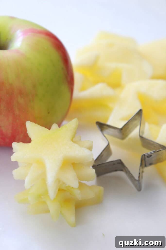 Patriotic Fruit Medley 3 A hand using a small star cookie cutter to create apple stars from sliced honey crisp apples.