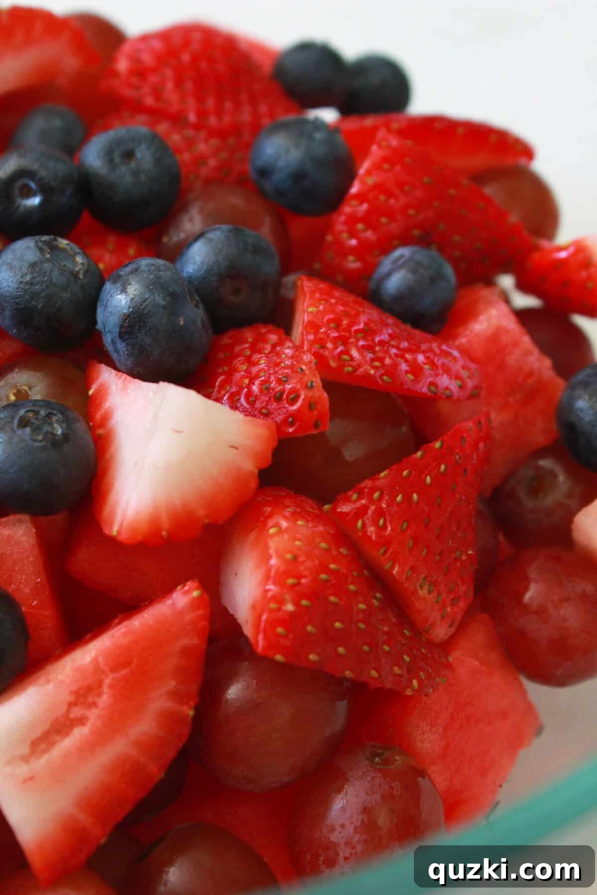 Patriotic Fruit Medley 4 A large mixing bowl filled with fresh red watermelon cubes, red grapes, sliced strawberries, and blue blueberries, ready for the simple syrup.