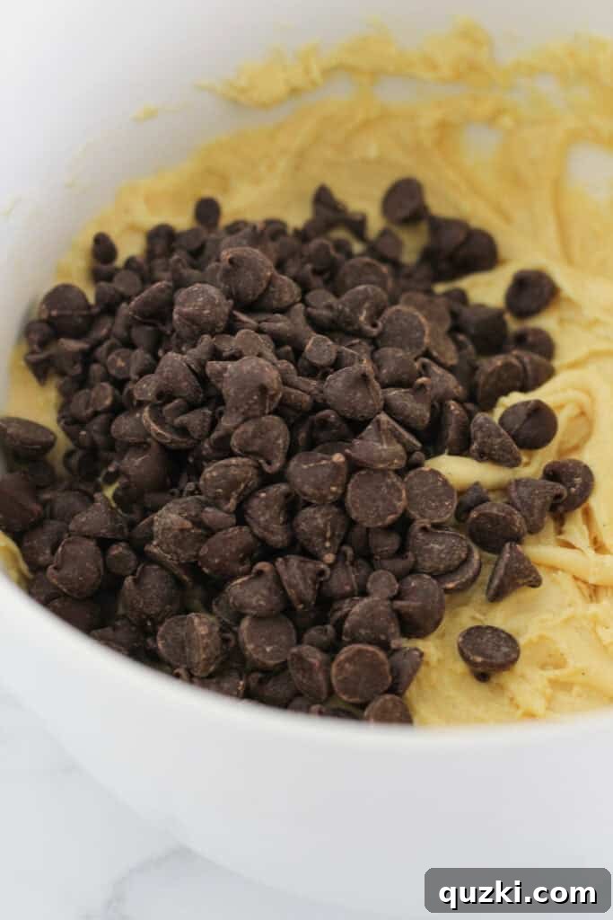 Adding the chocolate chips to the prepared cookie bar dough, ready for mixing.
