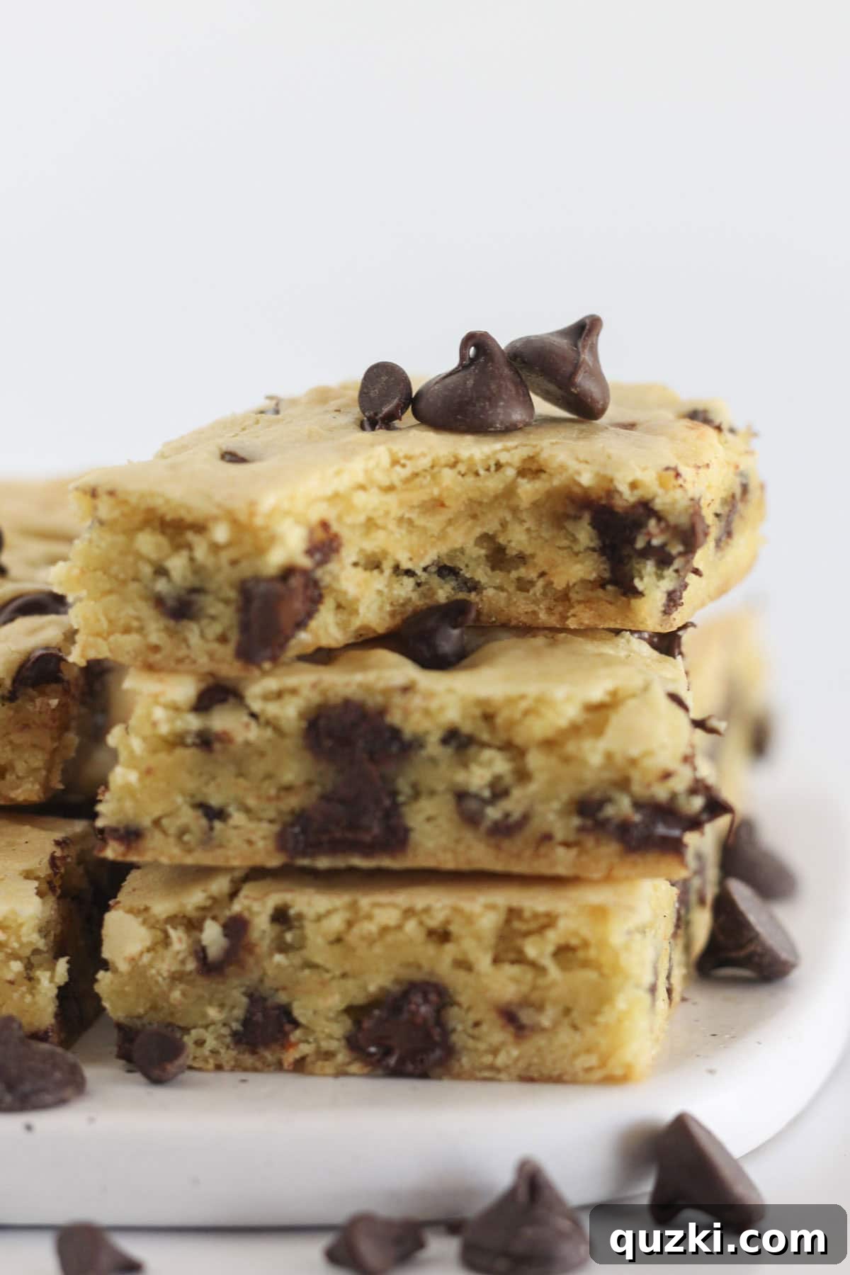 Stacked chocolate chip cookie bars with one bar showing a bite taken, highlighting the soft, chewy interior.