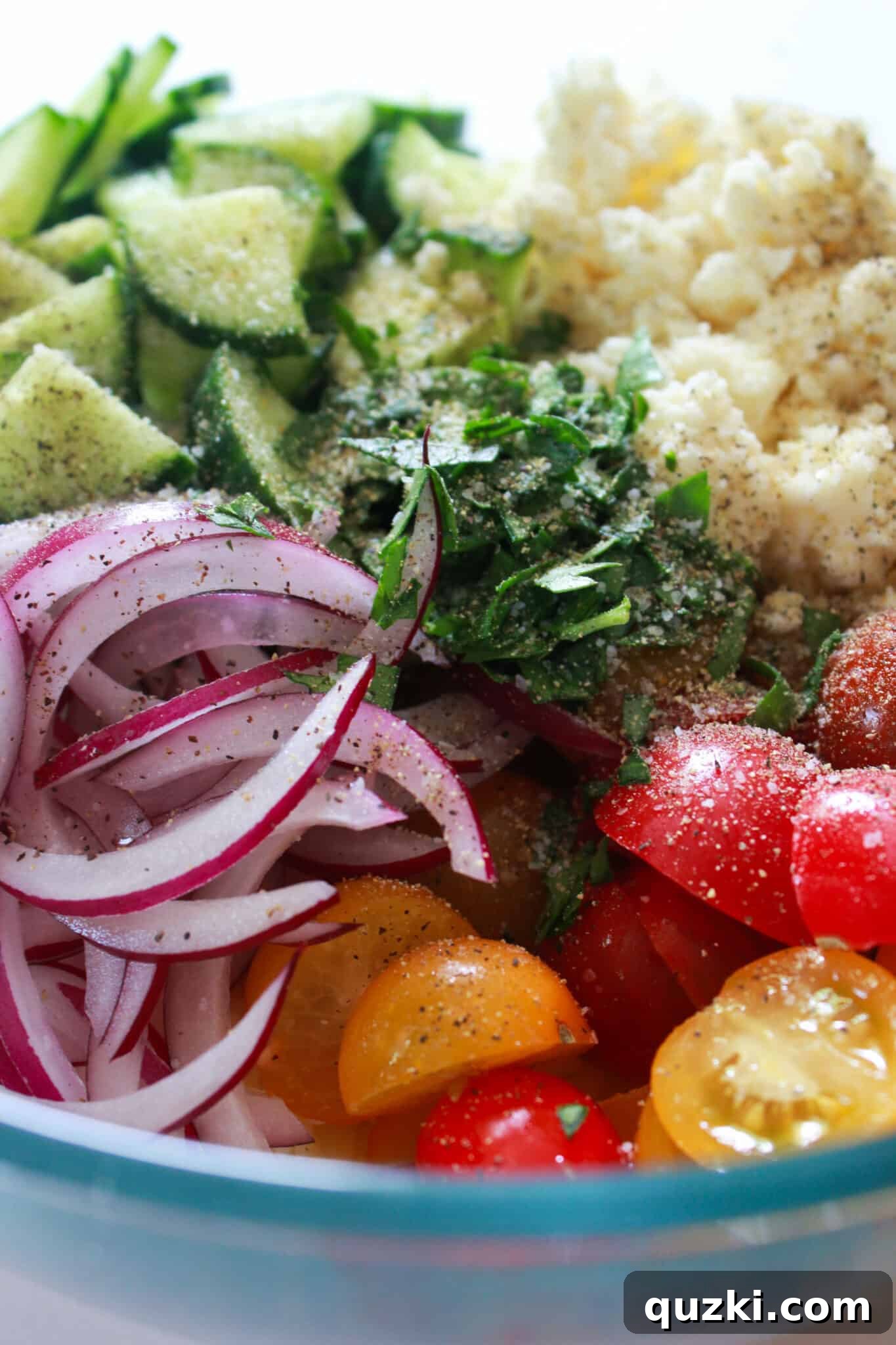 Adding diced vegetables, crumbled cheese, and fresh herbs to the Orzo Chickpea Salad.