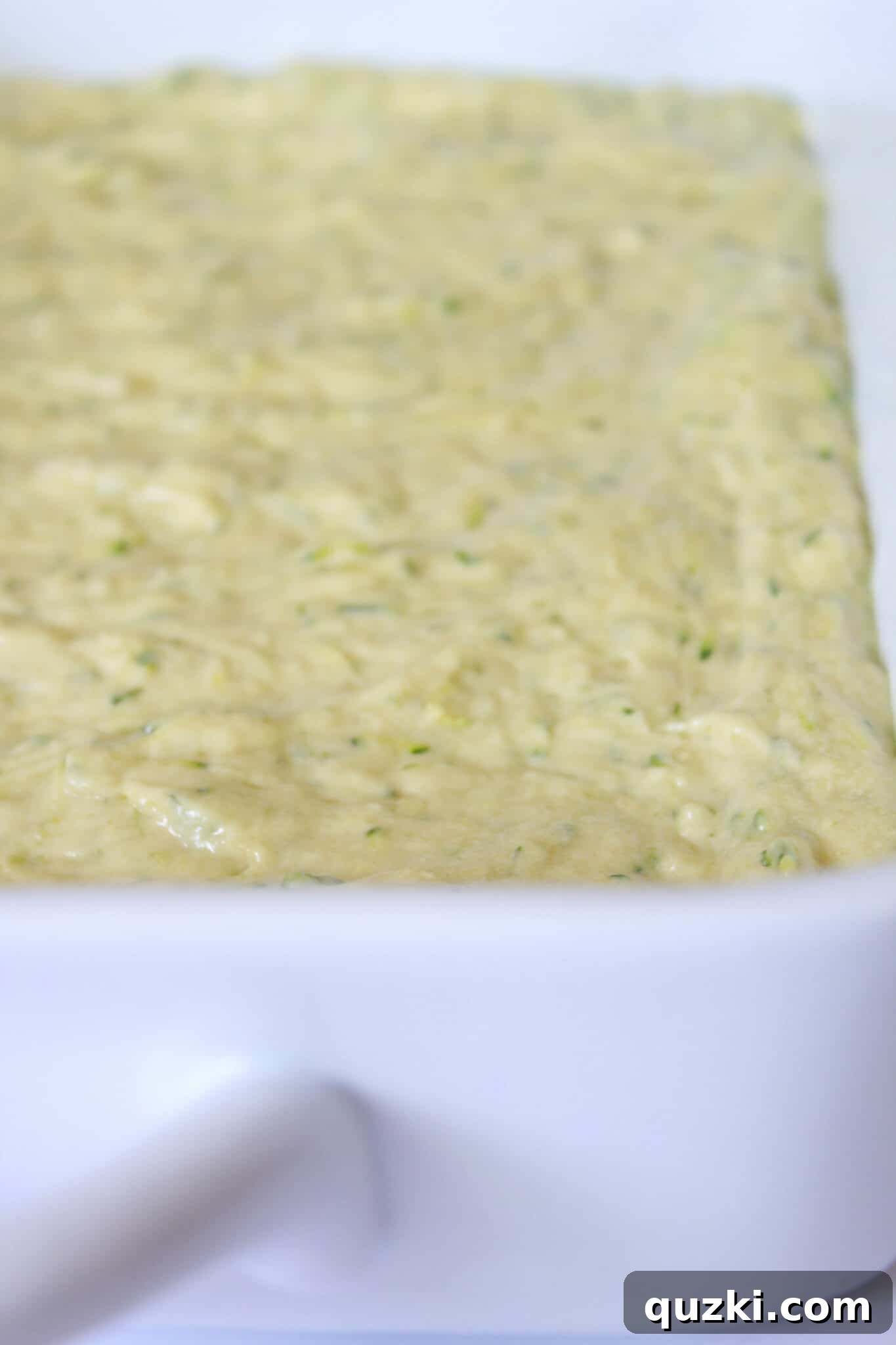 Effortless Zucchini Crumb Cake 8 Cake batter spread in a baking pan, with crumb topping ingredients waiting to be mixed in a separate bowl.