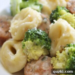 Serving of Easy Sausage Tortellini Skillet on a white plate, garnished with fresh basil.