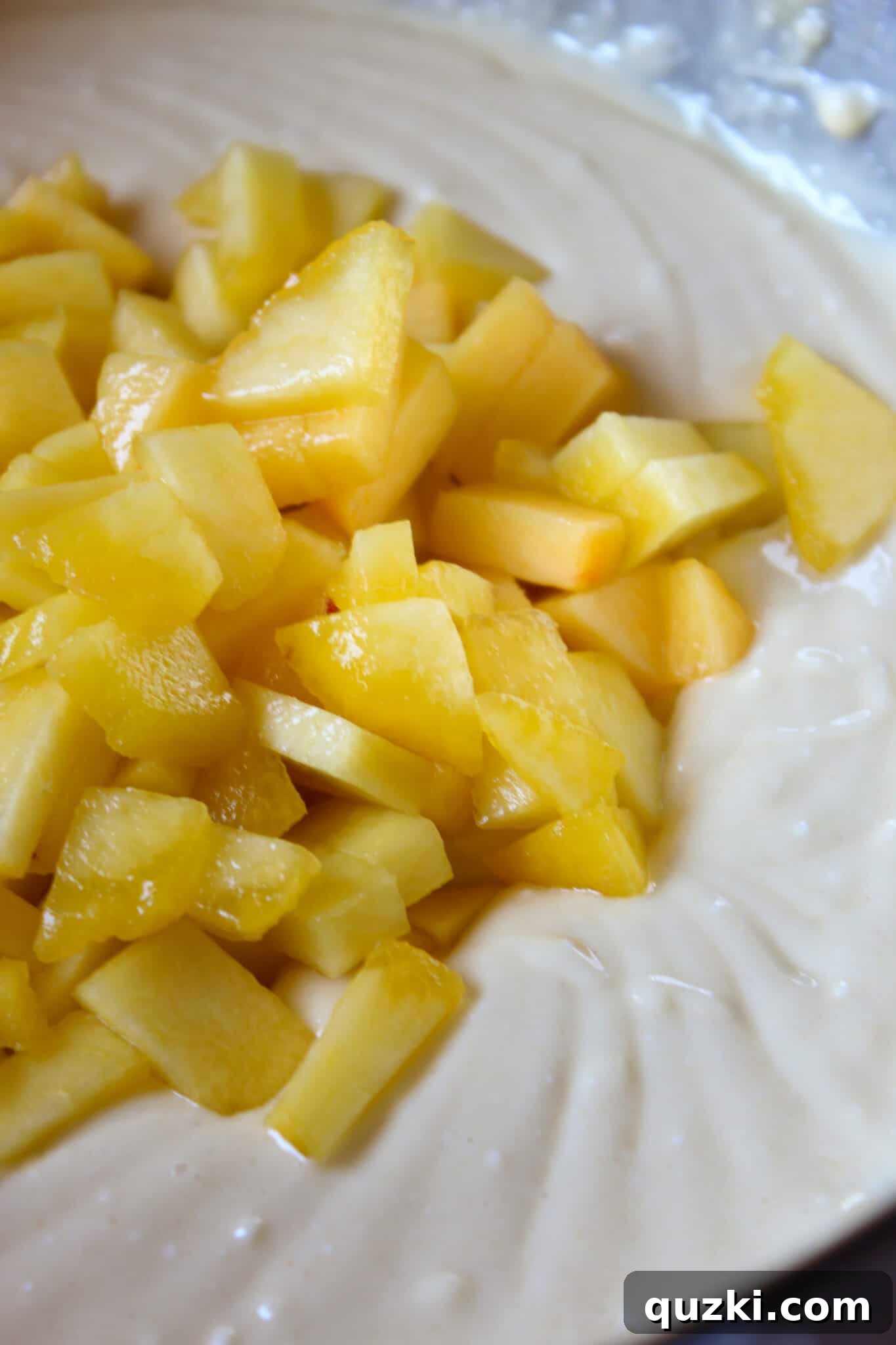 Effortless Peach Flip Cupcakes 7 Chopped peaches gently folded into the vanilla cake batter, ready for scooping.