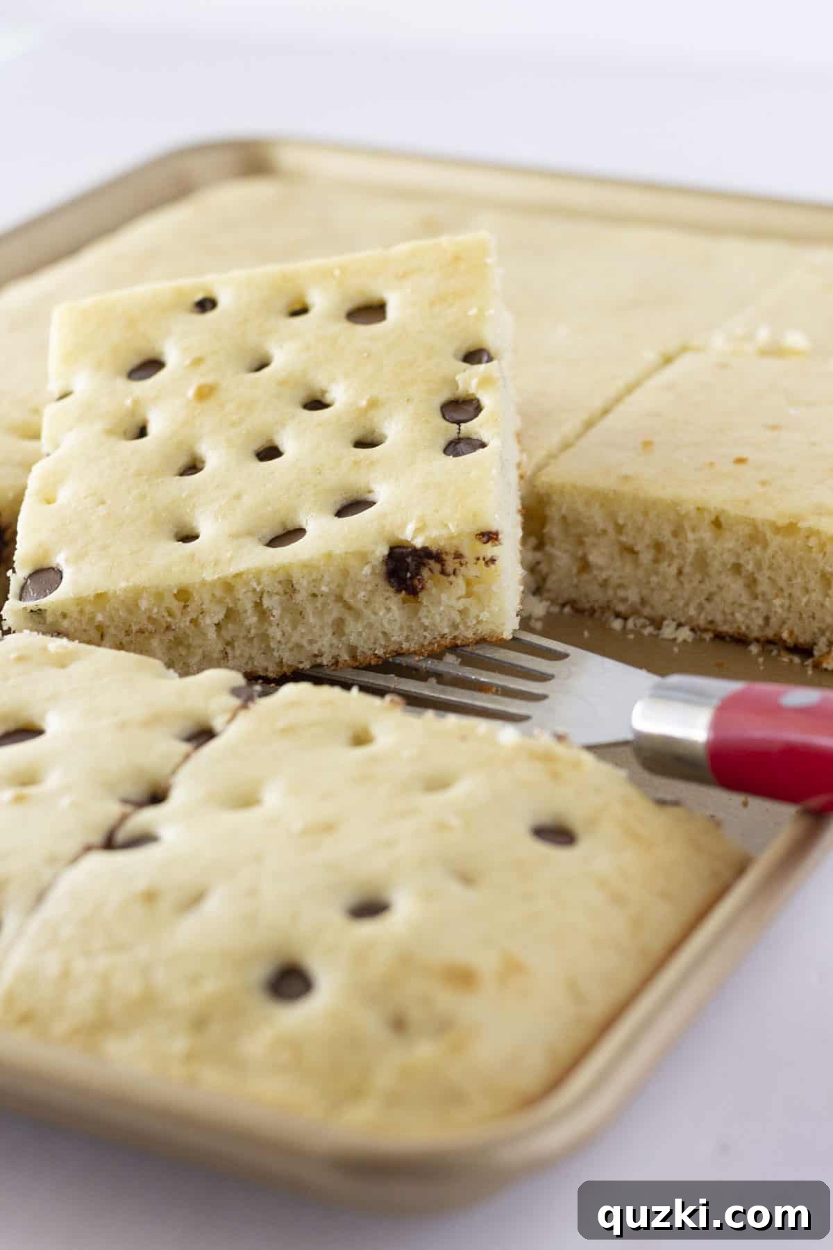 One-Pan Pancake Mix Magic 2 A large pan of golden-brown sheet pan pancakes, ready to be served, with a spatula on the side.