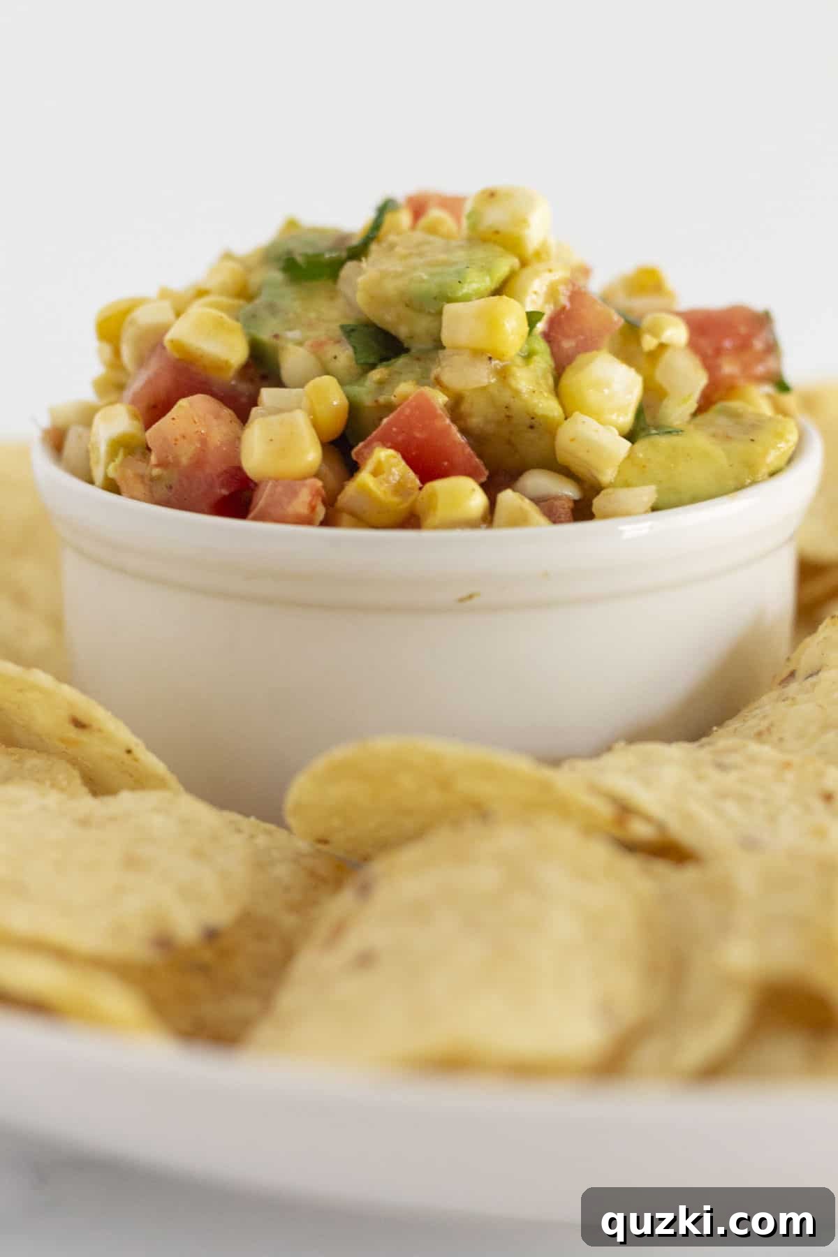 Vibrant Corn and Avocado Salsa 2 Bright and colorful corn and avocado salsa served in a bowl with crispy corn chips, ready for dipping.