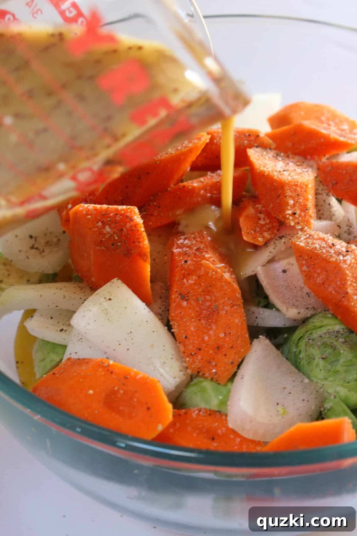 Tek Tepsi Sosisli Patates Lezzeti 11 Adding the vibrant honey mustard sauce to the seasoned vegetables in a large bowl.