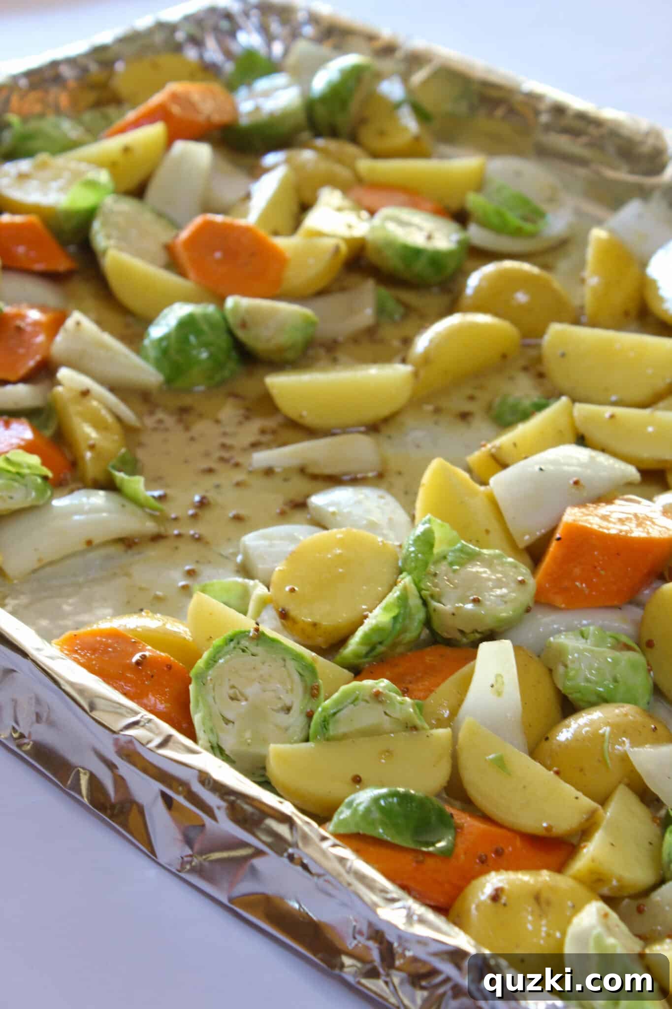 Tek Tepsi Sosisli Patates Lezzeti 12 Arranging the sauced vegetables in a single layer on a prepared sheet pan.