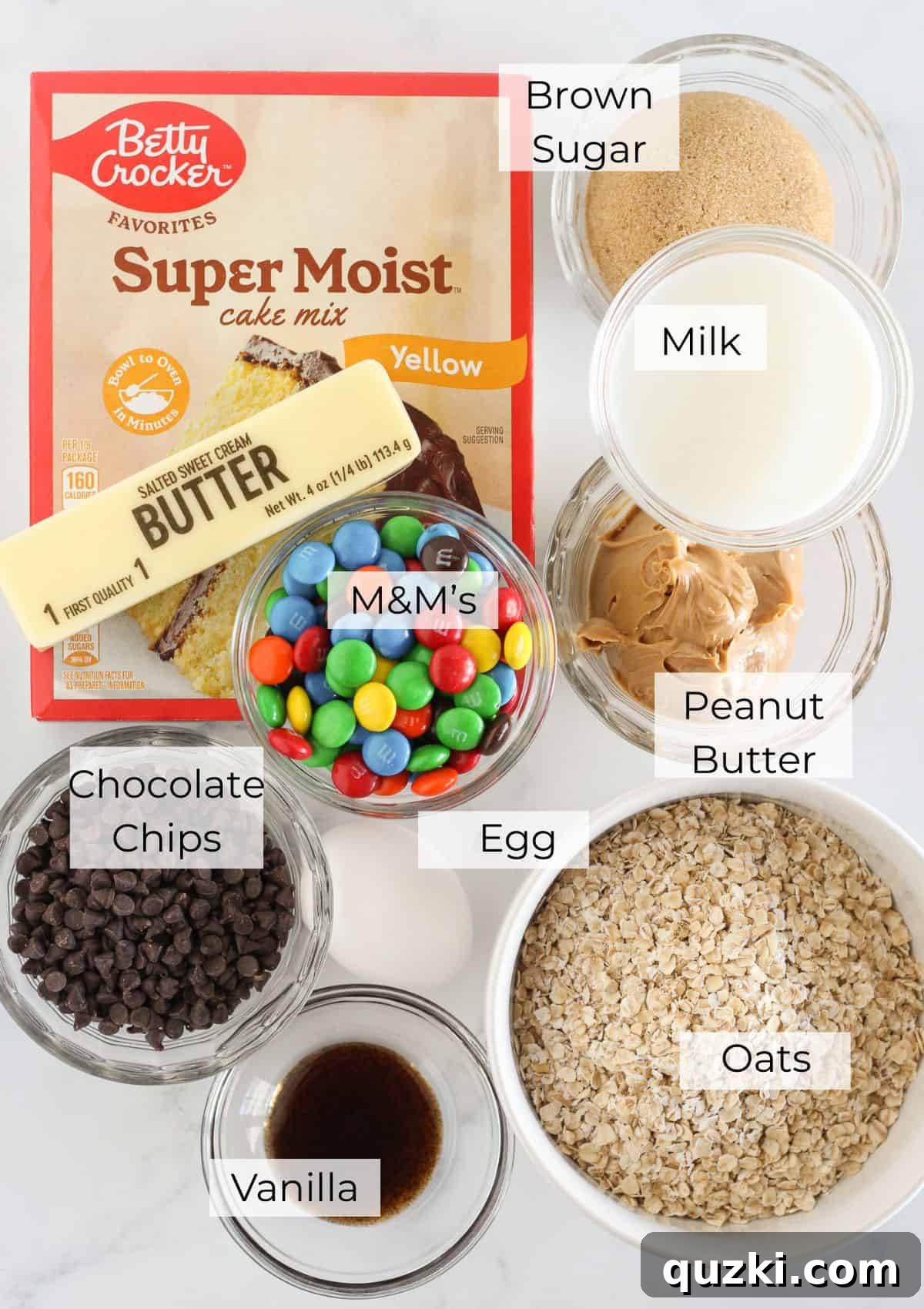 Ingredients laid out for making Monster Cookie Bars, including cake mix, oats, peanut butter, and candies.