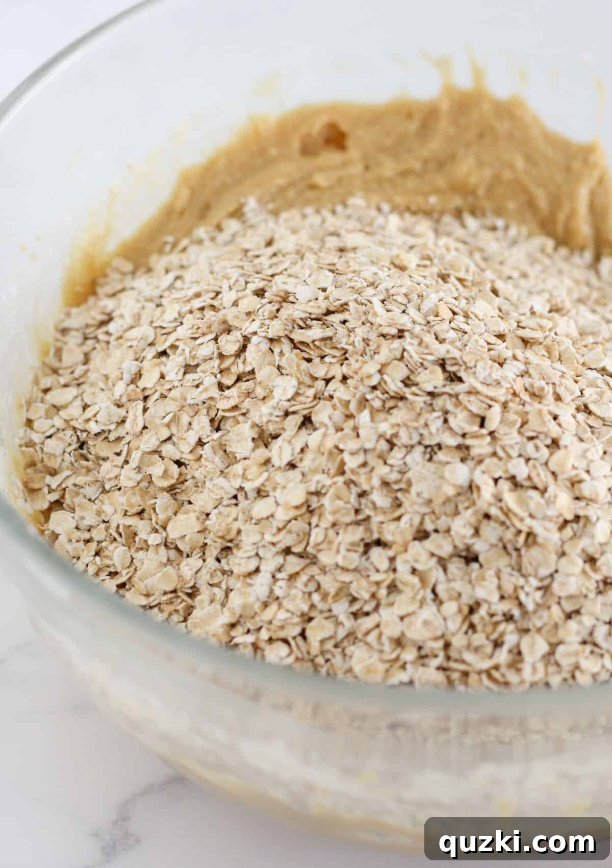 Adding quick oats to the thick cookie dough mixture.