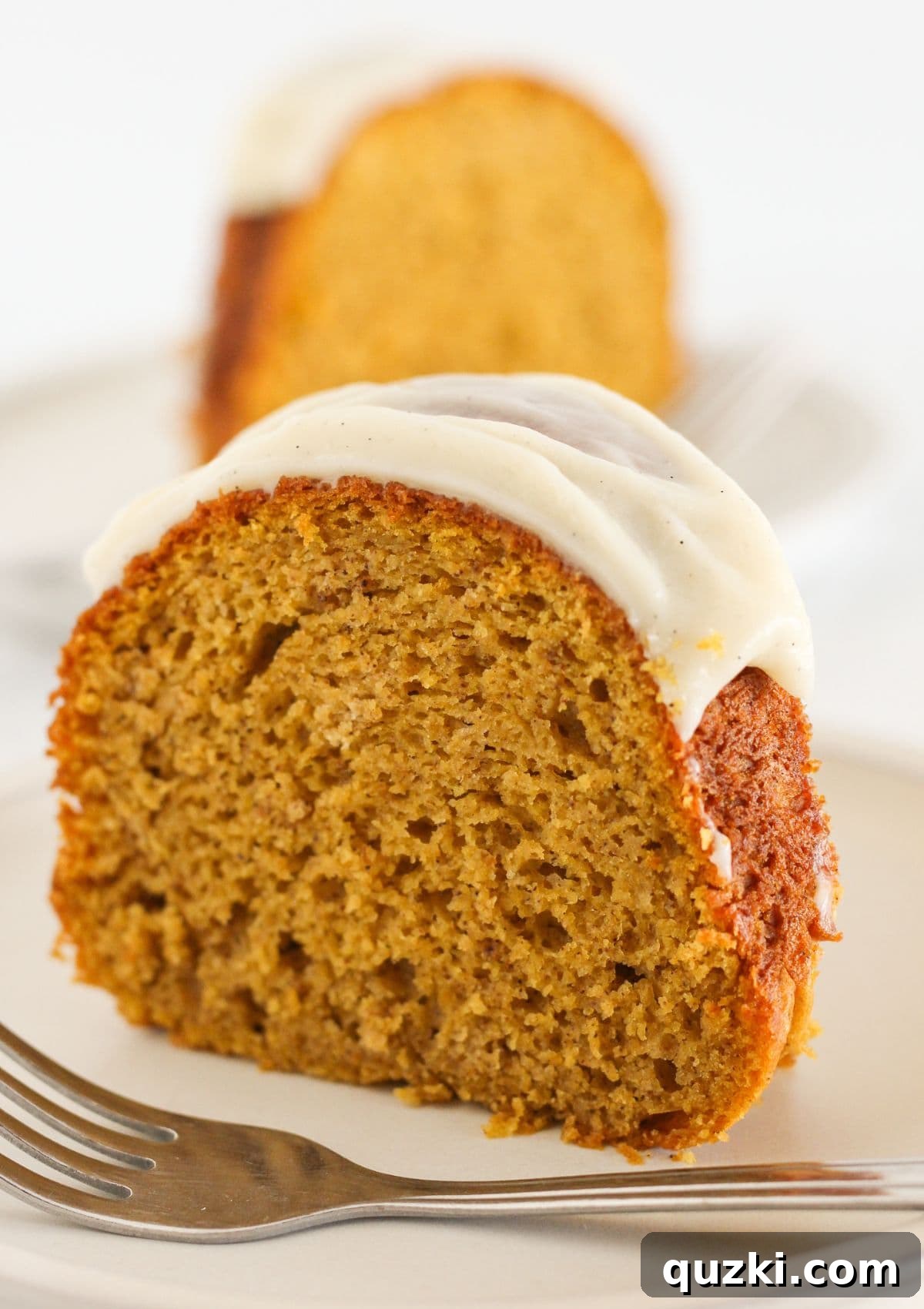 Two slices of pumpkin spice bundt cake, showing its moist texture and generous frosting.
