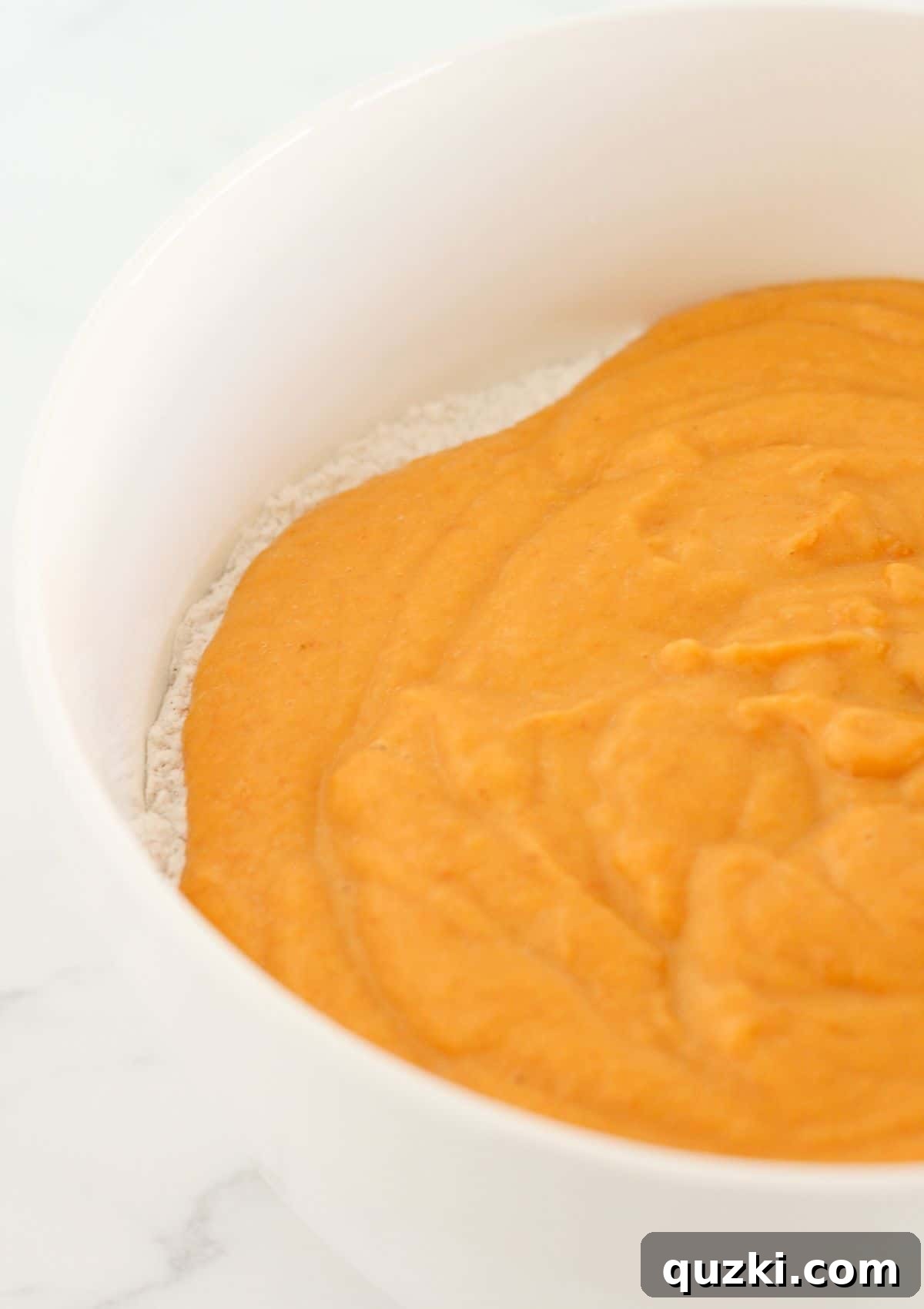 Combining the wet and dry ingredients to form the pumpkin spice bundt cake batter.