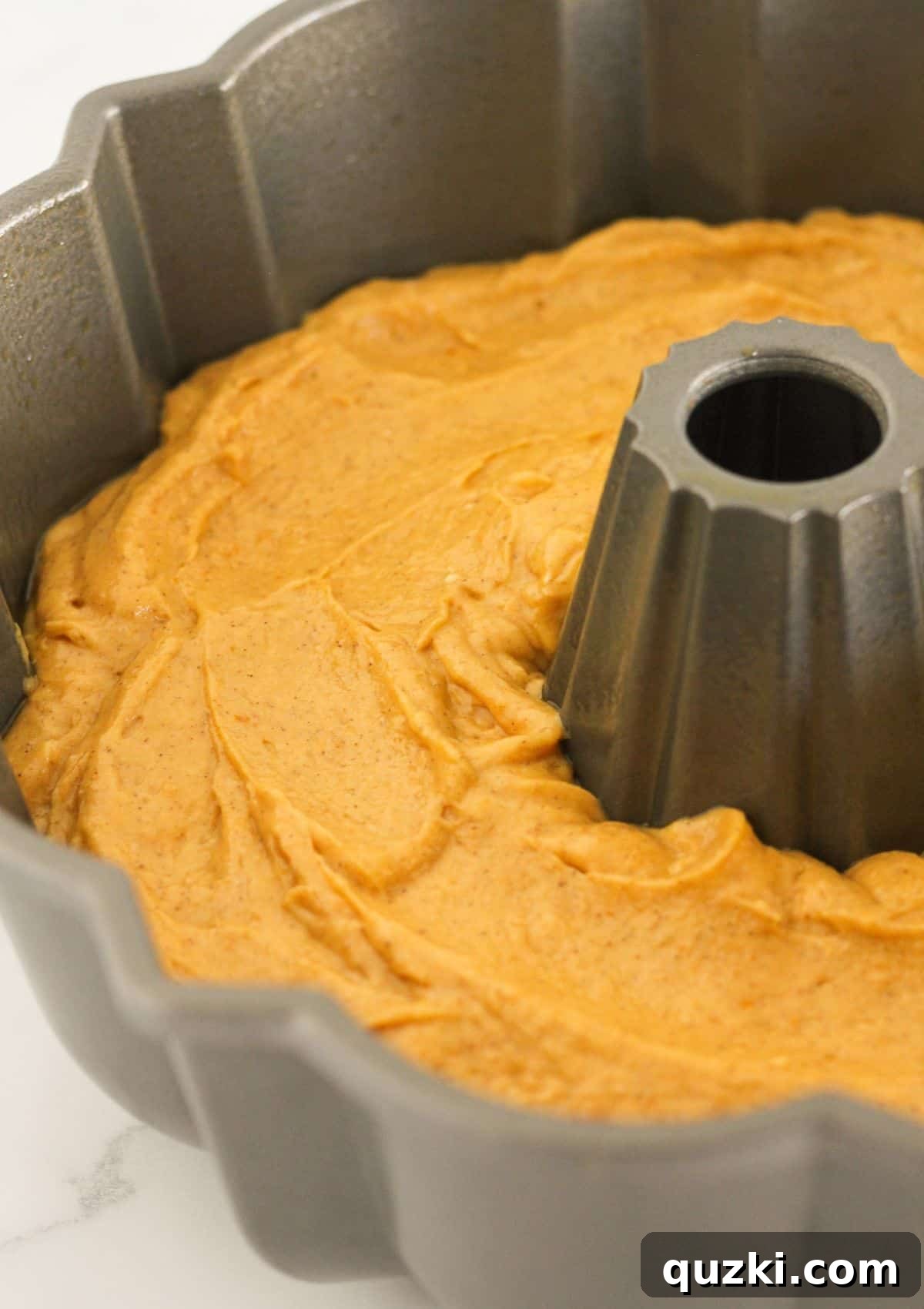 Pouring the pumpkin spice cake batter into a prepped bundt pan.
