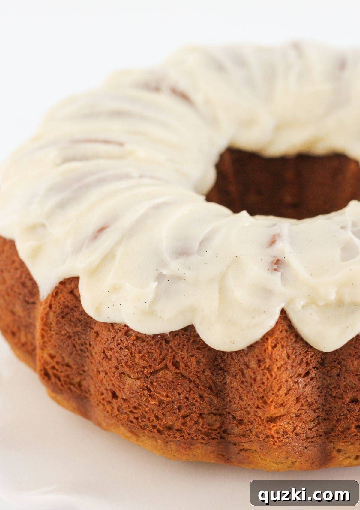 Drizzling homemade cream cheese frosting over a cooled pumpkin spice bundt cake.